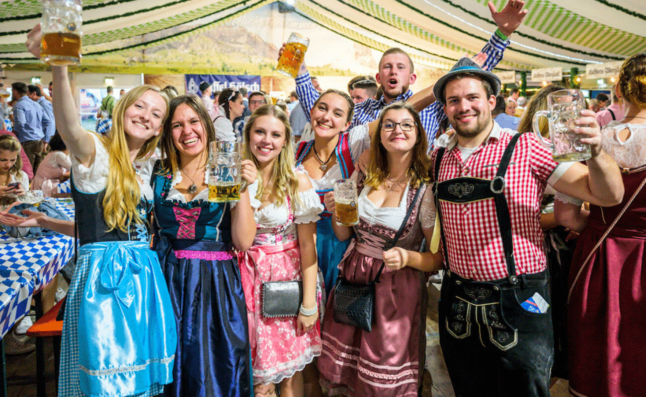 A lively Oktoberfest celebration in Newcastle city, featuring a diverse crowd of Caucasian and Hispanic individuals dressed in vibrant Bavarian costumes. People are joyfully raising beer mugs and enjoying traditional foods amidst a backdrop of colorful decorations. The atmosphere is filled with merriment and camaraderie, highlighted by traditional Bavarian symbols scattered throughout the scene. The image captures the essence of a festive gathering, radiating warmth and happiness.